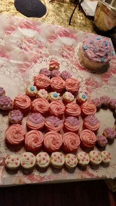 a table topped with lots of pink cupcakes