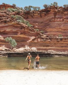 two people are wading in the water near some cliffs