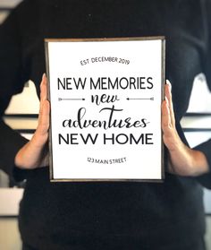 a person holding up a sign that reads new memories, new adventures, new home