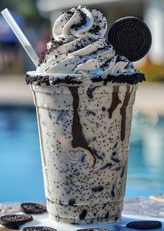 an ice cream sundae with oreo cookies on the table next to a pool