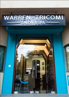 the front entrance of a salon and spa with blue walls, black doors and glass windows