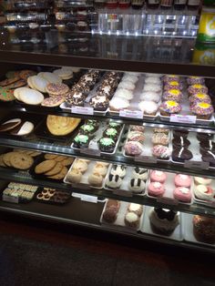 a display case filled with lots of different types of donuts and cookies on top of glass shelves