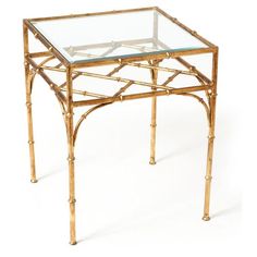 a glass topped table with gold bamboo frame and metal legs on an isolated white background