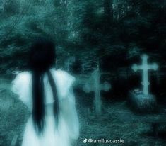 a woman with long hair standing in front of a cemetery