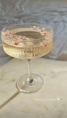 a glass filled with liquid sitting on top of a table next to a white bed