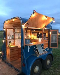 a food truck is parked in the grass with lights on it's roof and its door open