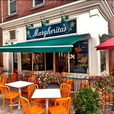 an outdoor restaurant with orange chairs and green awnings on the outside patio area