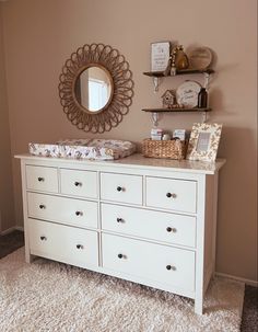 a baby's room with a dresser, mirror and other items on the wall