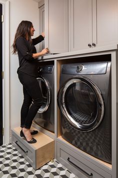 a woman standing on top of a washer next to a dryer in a room