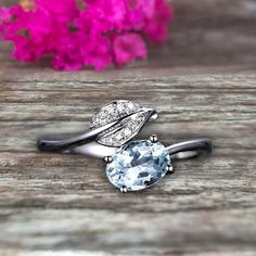 an engagement ring with a blue topazte and white diamond in the center on a wooden table