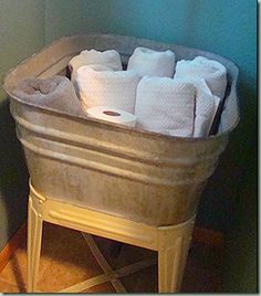 several rolls of toilet paper sit in an old tub on the floor next to a wall