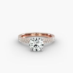 a rose gold engagement ring with diamonds on the band and a round brilliant center stone