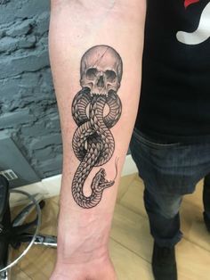 a skull and snake tattoo on the arm