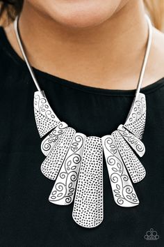 a woman wearing a black shirt and a silver necklace with intricate designs on it's neck