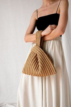 a woman wearing a white skirt holding a woven purse