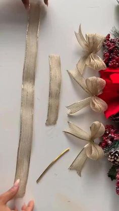 someone cutting ribbon with scissors on top of a white table next to christmas wreaths and pine cones