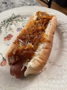 a hot dog on a bun with onions and ketchup sitting on a plate