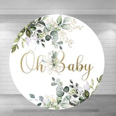 a round sign with the words oh baby painted on it and flowers in gold lettering