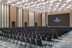 an empty conference room with rows of chairs and a projector screen on the wall