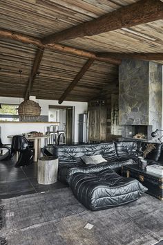 a living room filled with black furniture and a stone fire place next to a fireplace