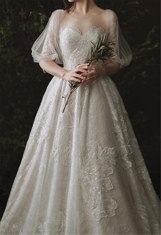 a woman in a wedding dress holding a flower and looking at the camera with her hands on her hips