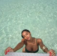 a woman sitting in the water with her eyes closed and hands resting on an object