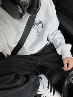 a young boy sitting in the back seat of a car with headphones hanging from his ears