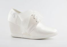 a white shoe with a bow on the side and laces at the top, against a white background