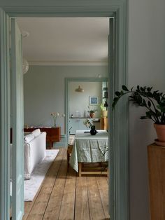 an open door leading to a living room and dining area with wood floors, white walls and green trim