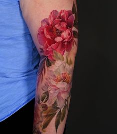 a woman's arm with flowers painted on it and leaves around the arm area