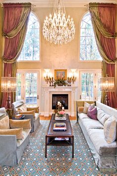 a living room filled with lots of furniture and a chandelier hanging from the ceiling