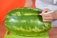 a person is writing on a large watermelon