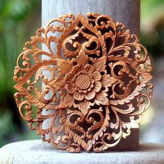 an intricate wooden brooch sits on top of a pillar