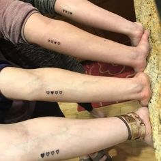 three people with matching tattoos on their arms and legs, both have hearts tattooed on them