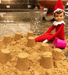 an elf is sitting in the sand with a magnifying glass next to it