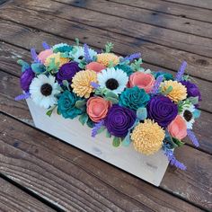 a wooden box filled with colorful flowers on top of a table