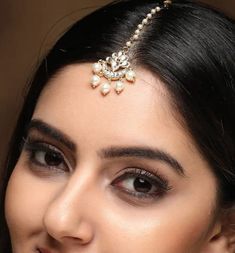 a close up of a woman wearing a head piece with pearls on it's forehead