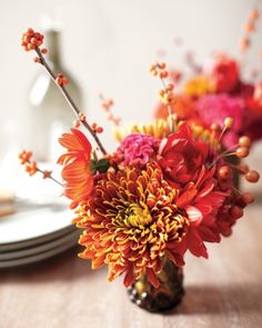 a vase filled with flowers on top of a table next to plates and utensils