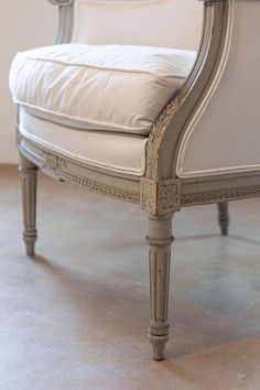 an antique chair with white upholstered cushions