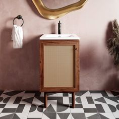 a bathroom with black and white tile flooring and a gold mirror on the wall