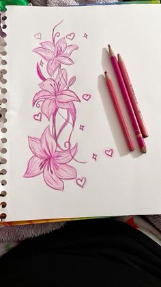 two pencils sitting on top of a paper with flowers and hearts drawn on it