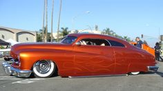 an orange car with flames painted on it's side parked in a parking lot