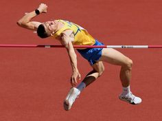 a man jumping over a high bar on top of a track