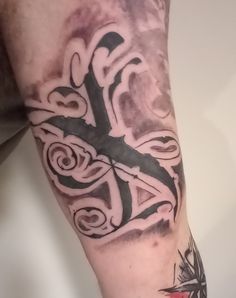 a man's arm with a cross tattoo on it and an arrow in the middle