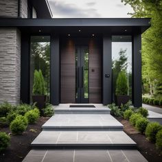 a modern entry way with steps leading up to the front door and landscaping around it