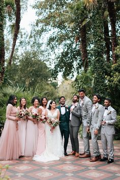 a group of people standing next to each other in front of some trees and plants