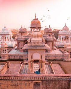 a man sitting on top of a building next to birds flying in the sky above