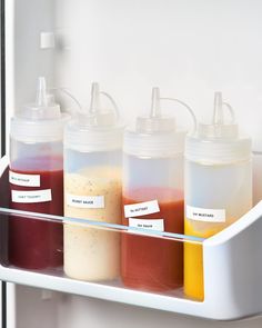 four bottles with different colored liquids in them sitting on a shelf next to each other