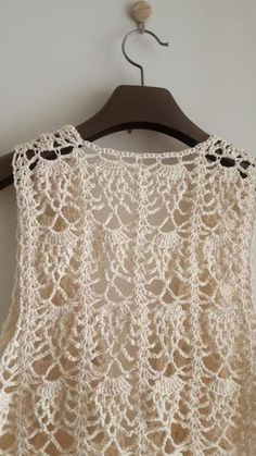 a crocheted top hanging on a wooden hanger