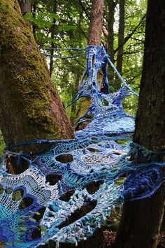 a blue piece of art hanging from a tree in the woods